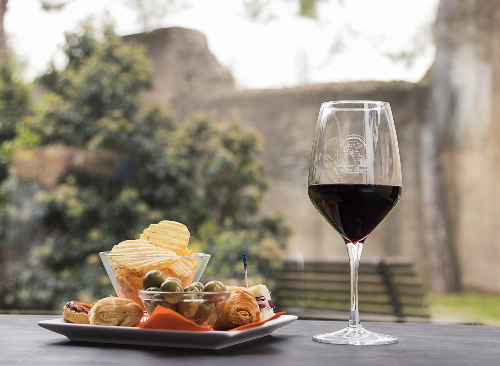 Calice di vino rosso brandizzato Pino Bar con finger food nel dehors